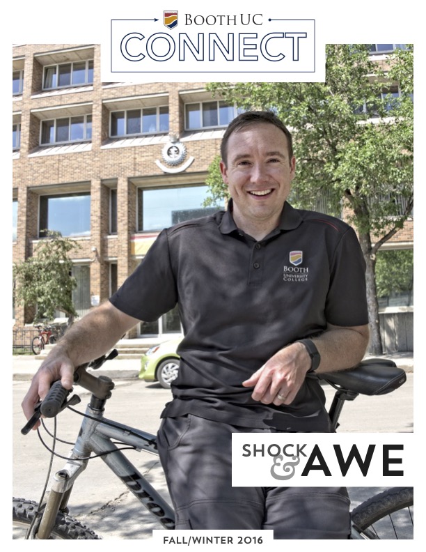 Male professor smiling and leaning on a bike in front of a school building with text overlay that says "Shock & Awe"
