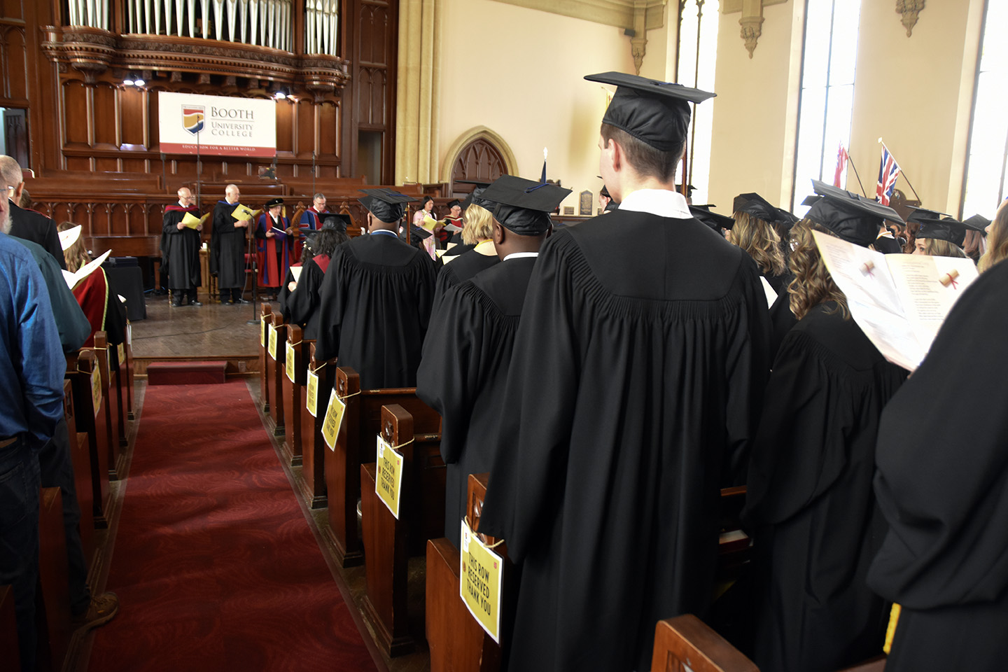 Graduates stand in their caps and gowns during a graduation ceremony.